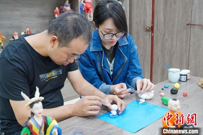 <a target='_blank'  data-cke-saved- >中新社</a>記者(右)現(xiàn)場體驗面塑制作過程?！￡悹帍?攝