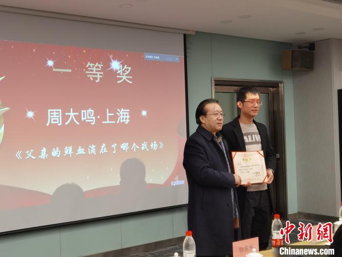 圖為作家、西北師范大學(xué)新聞與傳媒學(xué)院院長徐兆壽頒發(fā)一等獎證書，代領(lǐng)獎?wù)呱吓_領(lǐng)獎?！钅?攝