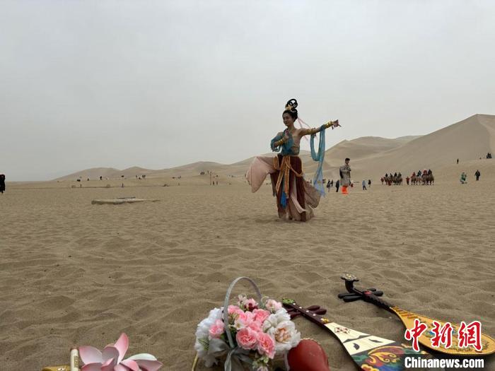 圖為2023年4月底，敦煌大漠“逐舞者”奧楠在鳴沙山月牙泉景區(qū)視頻直播敦煌舞?！●T志軍 攝