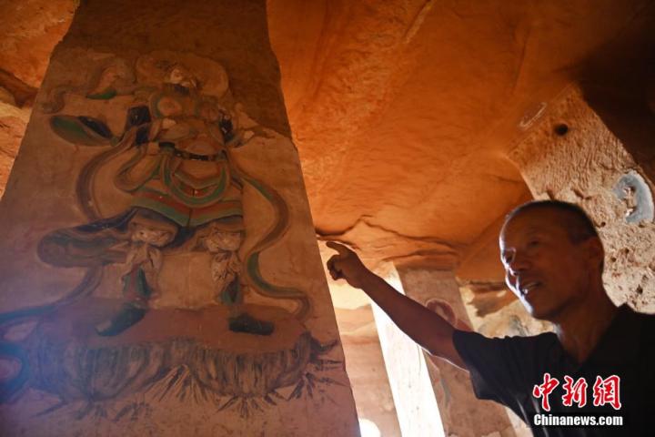 7月15日，甘肅省平?jīng)鍪袥艽h百里石窟長(zhǎng)廊羅漢洞石窟內(nèi)，該窟文保員郭建平介紹窟內(nèi)石刻彩繪壁畫。郭建平家中三代人曾自發(fā)保護(hù)羅漢洞石窟。羅漢洞石窟遺存40余個(gè)窟龕，以北魏至清代風(fēng)格為主。中新社記者 李亞龍 攝</p>
<p>